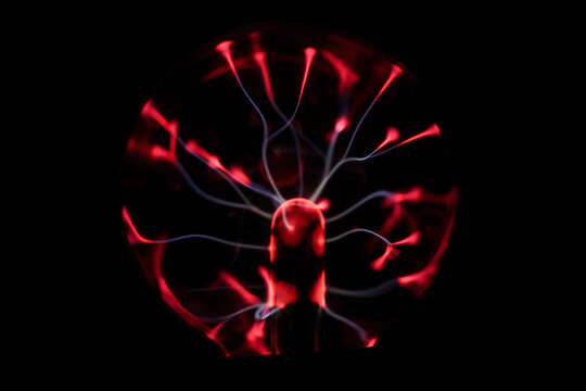 Full view of a red plasma globe with branching electric arcs glowing against a black background, abstract science, electricity and futuristic energy concept