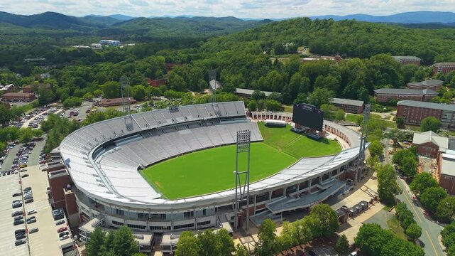 Charlottesville, Virginia, impressive aerial drone view looking down over Scott Stadium at the University of Virginia, showcasing the green football field, stadium seating, and surrounding forested hi