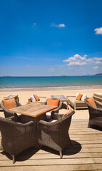Beachfront cafe in Quy Nhon, Vietnam, with tables, chairs and sunshades overlooking the sea, gentle waves and fishing boats in the background on a sunny day. © Olga Khoroshunova