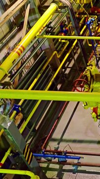 Industrial yellow pipelines and valve cluster, closeup of flanged joints, red handwheels, blue actuators and pressure gauges on dense piping network inside plant maintenance area