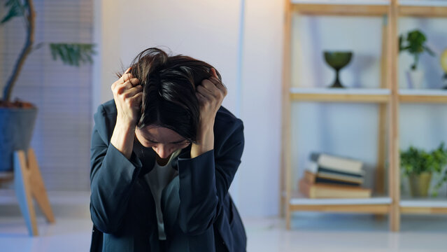 暗い部屋で落ち込むミドル女性。悩み、不安、心配、ストレス、うつ、絶望、メンタルヘルス、後悔、失敗