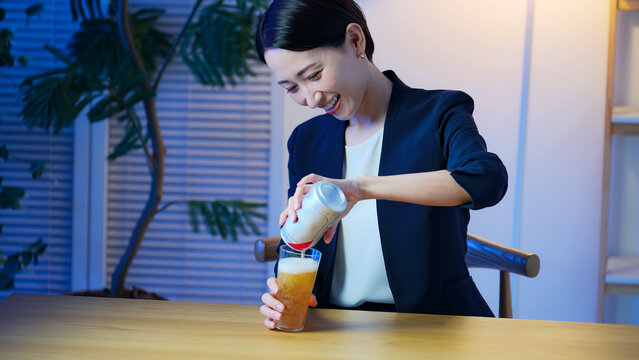 缶ビールをコップに注ぐミドル女性。お酒、アルコール、笑顔、宅飲み、晩酌、飲み会、