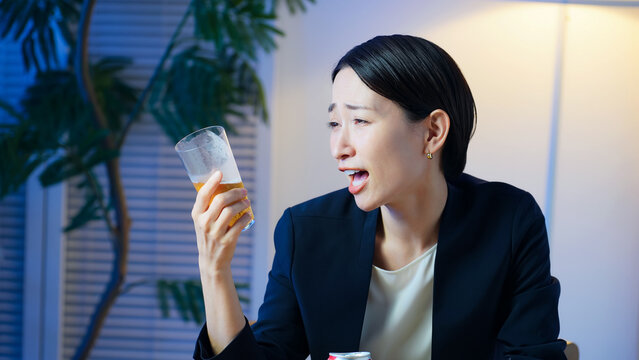 暗い部屋でお酒を飲む女性。ビール、ウイスキー、飲み会、居酒屋、バー、スナック、宅飲み