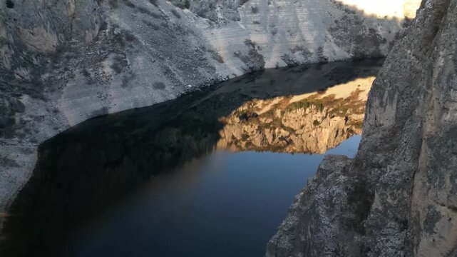 Aerial drone flight over Blue Lake (Modro Jezero) in Imotski, Croatia surrounded by dramatic limestone cliffs