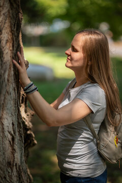 Close-up of a blind woman exploring tree bark texture through touch in a sunny Park