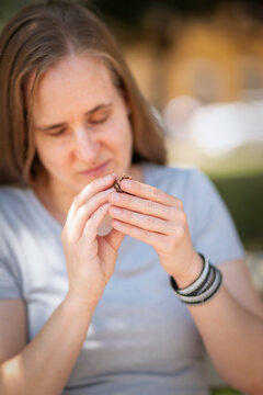 Visually impaired woman exploring a pine cone with tactile sense outdoors