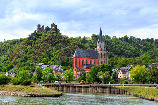 Oberwesel along the Rhine River in Rhineland-Palatinate, Germany, featuring the striking red-accented Liebfrauenkirche (Church of Our Lady) and Sch&ouml;nburg Castle perched on the wooded hill above