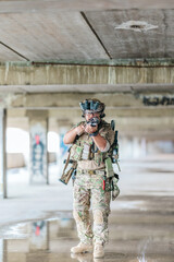 Naklejka premium Military tactical operator holds rifle while clearing abandoned concrete building interior