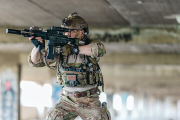 Fototapeta premium Military tactical operator holds rifle while clearing abandoned concrete building interior
