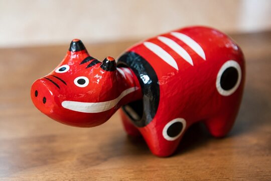 Red and black nodding cow folk toy on simple wooden background