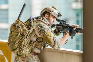 Fototapeta premium Military tactical operator holds rifle while clearing abandoned concrete building interior