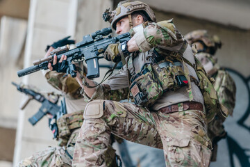 Fototapeta premium Military tactical operator holds rifle while clearing abandoned concrete building interior