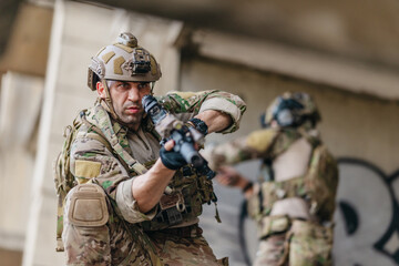 Fototapeta premium Military tactical operator holds rifle while clearing abandoned concrete building interior