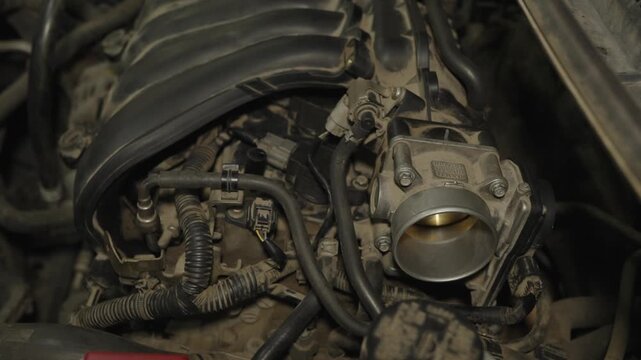 Close-up of a dusty car engine block with a throttle body valve.