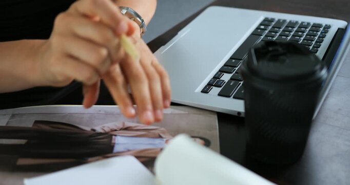 Focus on hands drafting alongside hot beverage. Person engaged in digital and traditional planning tasks. Individual meticulously working on computer and jotting notes with coffee nearby