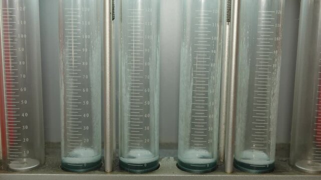 Close-up of glass graduated cylinders on a fuel injector testing diagnostic bench.