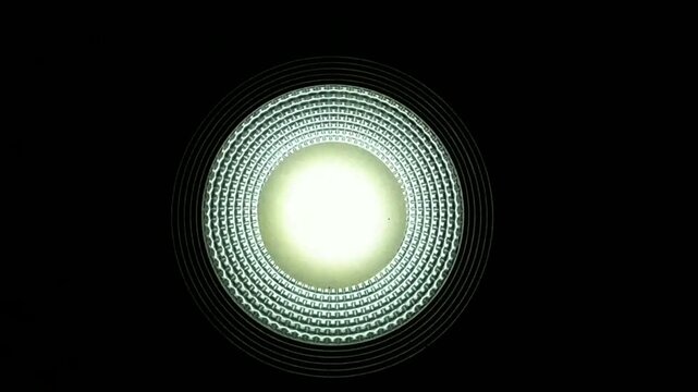 Close-up view of a bright LED ceiling light filmed from directly below, featuring subtle flickering illumination against a dark background, ideal for lighting, technology, and abstract visuals.