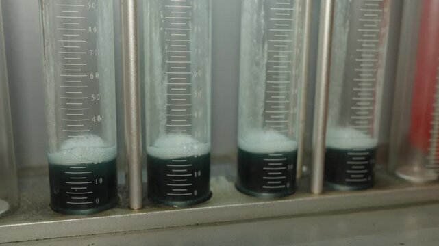 Close-up of glass graduated cylinders on a fuel injector testing diagnostic bench.