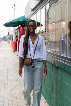teenage girl with an Afro braid hairstyle walking down a shopping street