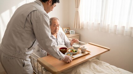 Fototapeta premium 病院のベッドで寝たきりの高齢患者に対し、日本の伝統的な病院食の介助を行う介護士