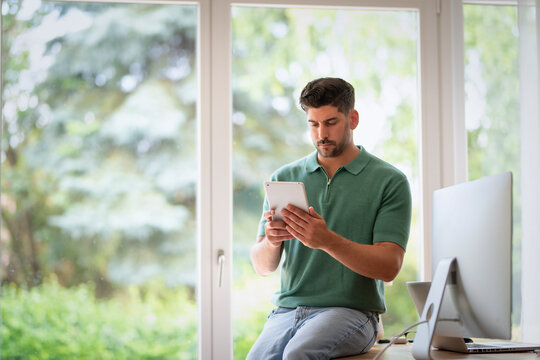 Handsome man using tablet by the window in a bright modern home