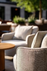 Fototapeta premium Modern outdoor lounge area with cushioned armchairs and small wooden table. Comfortable patio furniture for exterior relaxation. Stylish terrace setup for hospitality and luxury design.