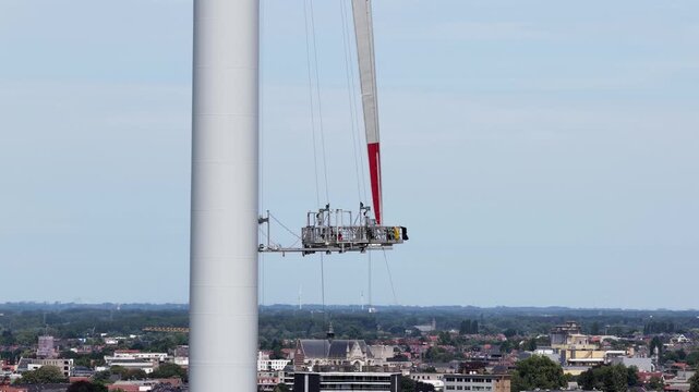 Technicians descending a wind turbine on a maintenance platform
