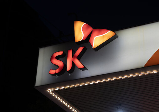 SK corporation brand logo sign and corporate identity display at night with warm lighting and a clean dark background, Close-up of an illuminated SK logo.