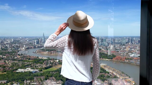 Rear view of a tourist woman looking at the panoramic view of the skyline of London, England, during a sunny summer day