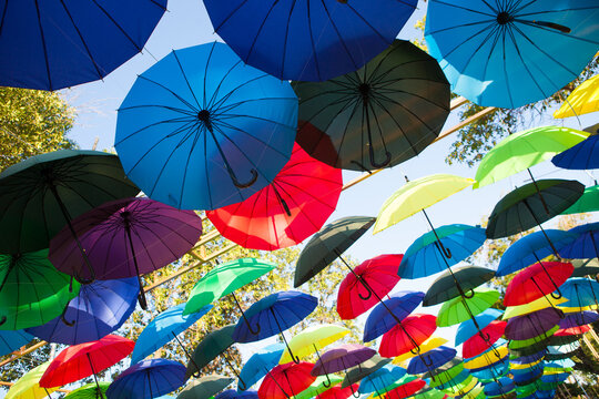 Rows of colorful umbrellas stretch across the sky in a vivid outdoor display, festive street decoration, creative travel background.