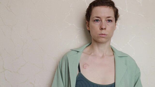soft portrait of a woman with a visible implanted port and slight smile, illustrating recovery, self acceptance and authentic daily life after cancer treatment