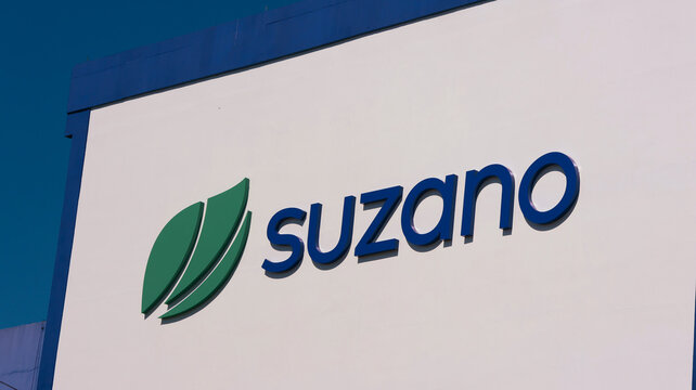 Detalhe da fachada industrial da Suzano com logotipo corporativo em destaque, simbolizando produ&ccedil;&atilde;o regional de celulose, papel e atividade econ&ocirc;mica local. Suzano, SP, 04 de agosto de 2026