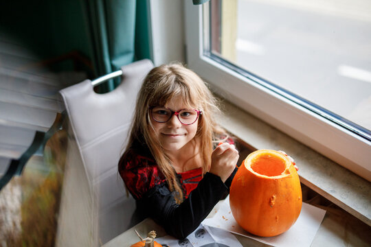 Little girl and big pumpkin for Halloween. Child making jack-o-lanterns