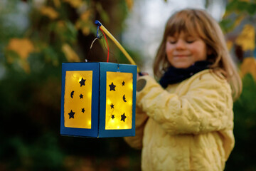 Closeup of little preschool kid girl holding selfmade traditional lanterns with candle for St. Martin procession. child happy about family parade in kindergarten. German tradition Martinsumzug © Irina Schmidt
