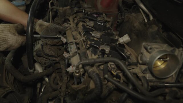 Mechanic tightening bolts with a ratchet wrench on a car engine.