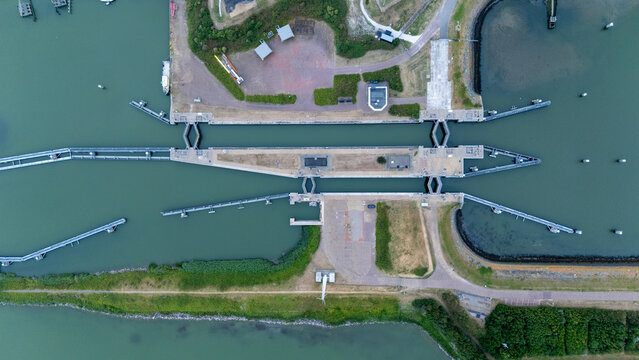 Top down drone view of the Lorentzsluizen on the Afsluitdijk in the Netherlands, showing the lock complex, waterway infrastructure and surrounding landscape from above.