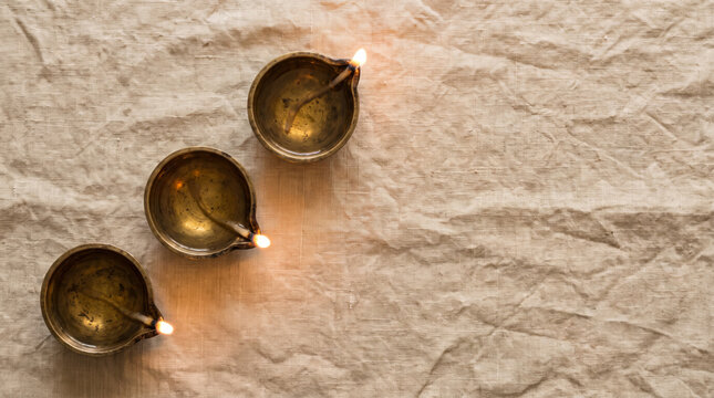 Minimalist Diwali flat lay with diya candle and marigold petals on muted pastel background, 45-degree angle, right copy space, variation 02