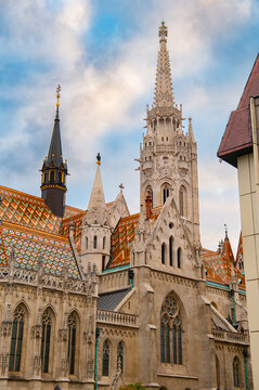 Matthias Church and colorful tiled roof against cloudy sky in Budapest, Hungary.