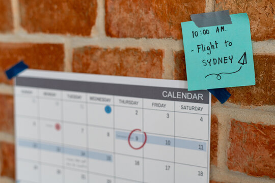 Calendar on brick wall with note for 10 AM flight to Sydney.