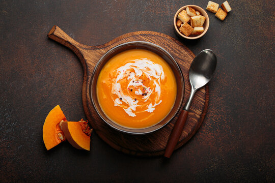 Pumpkin soup croutons cream fresh pumpkin slices wooden board dark background autumn winter