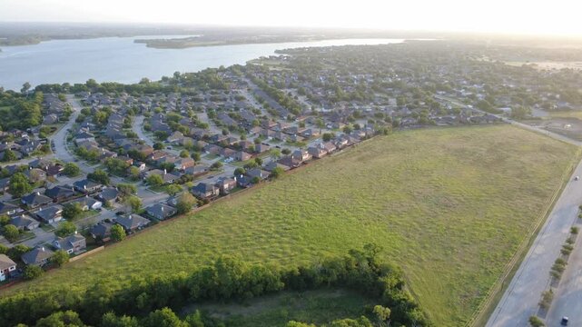 Fenced suburban property lines meet undeveloped green expanses overlooking expansive Lewisville Lake shorelines within Lakewood Estates. Continuous residential layouts span Little Elm, DFW