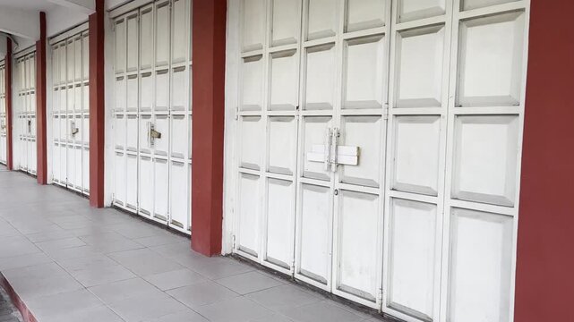 Closed white folding metal gate shutter of a storefront shop
