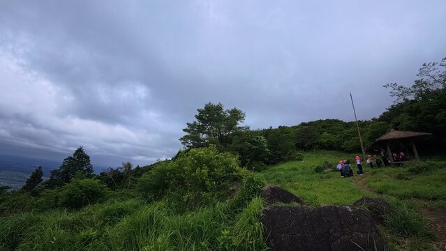 Lush green grassy slope of a mountain with a small shelter in the distance
