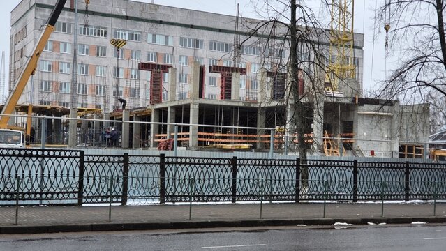 Construction site of a building with cranes and workers in an urban area during winter