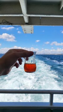 Holding a glass of tea on a boat ride through open water in daylight