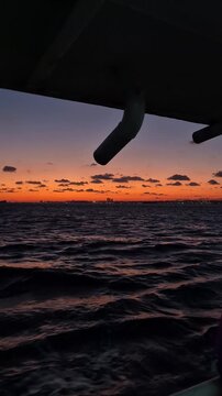Sunset over the ocean with clouds and distant boats at a coastal location