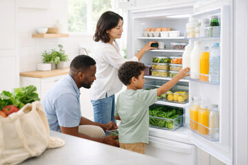 Family organizing fridge with fresh groceries, focus on healthy food and storage © dvoevnore