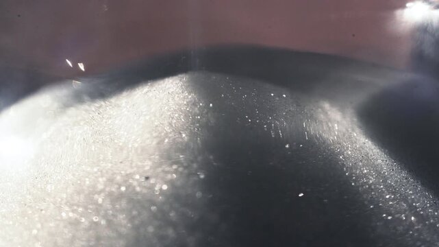 White Sand Falling on Pile in Classic Hourglass Measuring Time Passage