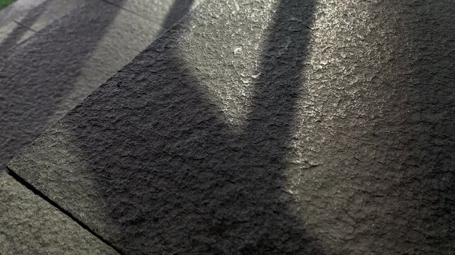 Parallel shadows stretch across stone pavement