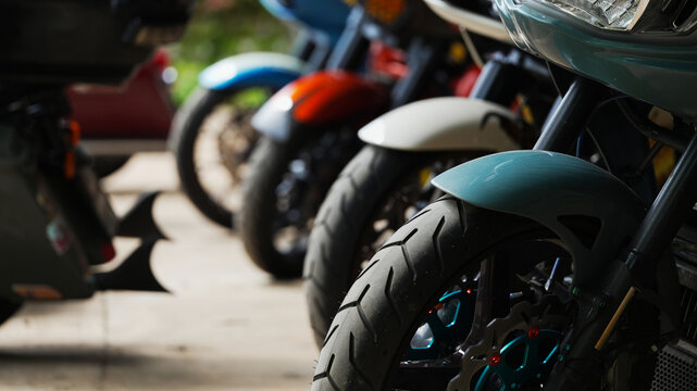 Row of touring motorcycles parked with selective focus on front wheel